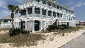 Ein zweigeschossiges Strandhaus mit einem Balkon und einer Treppe, die zum Eingang führt.