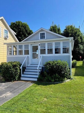 Une maison de plain-pied avec un porche à l’avant, un escalier menant à l’entrée et un petit jardin devant.