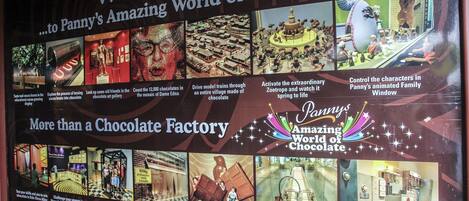 A promotional display for Panny's Amazing World of Chocolate, featuring various chocolate-themed attractions and activities.
