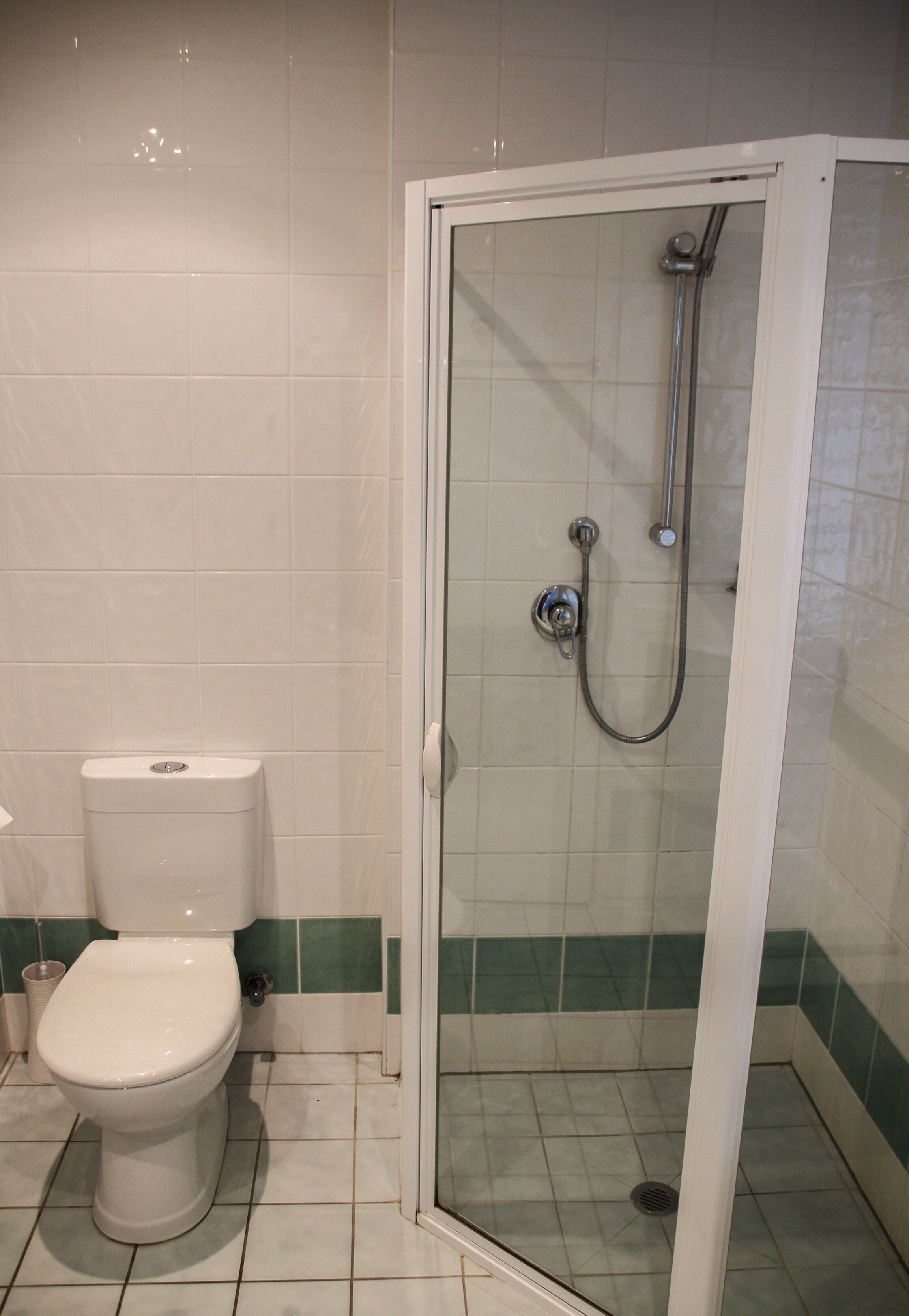 A bathroom with a toilet, a shower enclosure, and tiled walls.