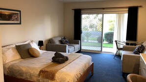 A hotel room with a bed, a sofa, a desk, and a view of the outdoors. - 110 @ Waves Phillip Island.  FREE WIFI & LINEN (Cowes)