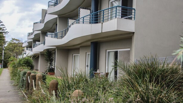 A modern multi-story building with balconies, a pathway, and surrounding vegetation. - 110 @ Waves Phillip Island.  FREE WIFI & LINEN (Cowes)