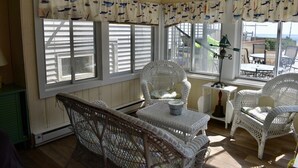 Ein sonnendurchflutetes Zimmer mit Korbmöbeln, einem Tisch und einem Schild mit der Aufschrift 'TO LIFE BOATS'.