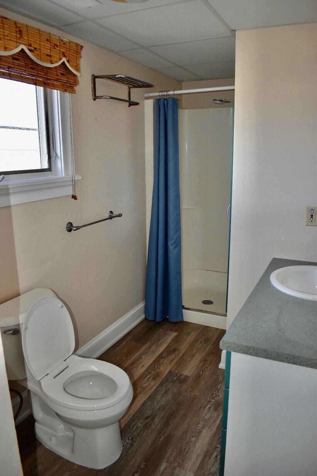 A bathroom with a toilet, a shower with a blue curtain, and a sink.