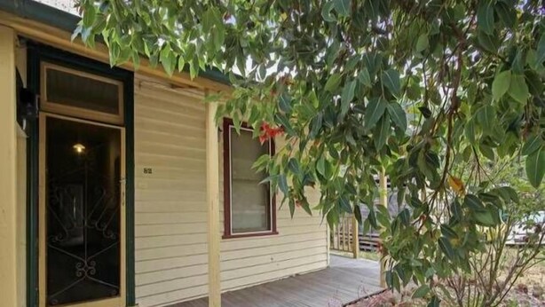 Une maison de plain-pied avec une terrasse en bois, une porte d’entrée et une fenêtre.