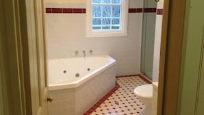 Une salle de bain avec une baignoire, des toilettes et une fenêtre.