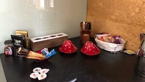 Una encimera de cocina con equipo para preparar café, incluyendo una cafetera, cápsulas de café, un hervidor y un molinillo.