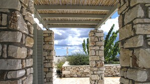 A stone-walled outdoor area with a pergola overhead, leading to a covered patio. - Villa Mella, Paros: Idyllic waterfront Villa that combines privacy & relaxation. (Paros)