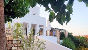 A modern building with a stone staircase leading to a white structure with columns. - Villa Mella, Paros: Idyllic waterfront Villa that combines privacy & relaxation. (Paros)