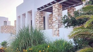 A modern building with a white facade, stone pillars, and a covered outdoor area. - Villa Mella, Paros: Idyllic waterfront Villa that combines privacy & relaxation. (Paros)