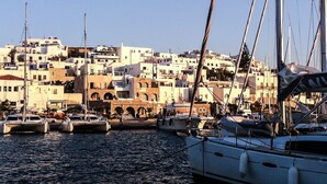 A harbor with boats docked, a clear sky, and a densely packed town with white buildings in the background. - Villa Mella, Paros: Idyllic waterfront Villa that combines privacy & relaxation. (Paros)