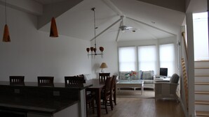 A spacious living area with a dining table, chairs, a sofa, and a TV.