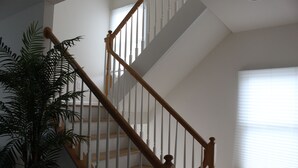 A staircase with wooden railings and white balusters, leading to an upper floor.