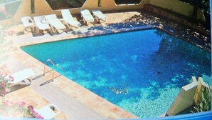 A swimming pool with lounge chairs and a small deck area.