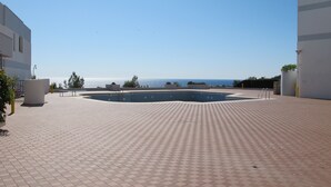 A rooftop pool area with a clear view of the sea, surrounded by buildings.