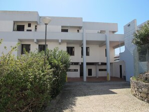 Un edificio moderno con varios pisos, un patio con pavimento de adoquines y una farola.