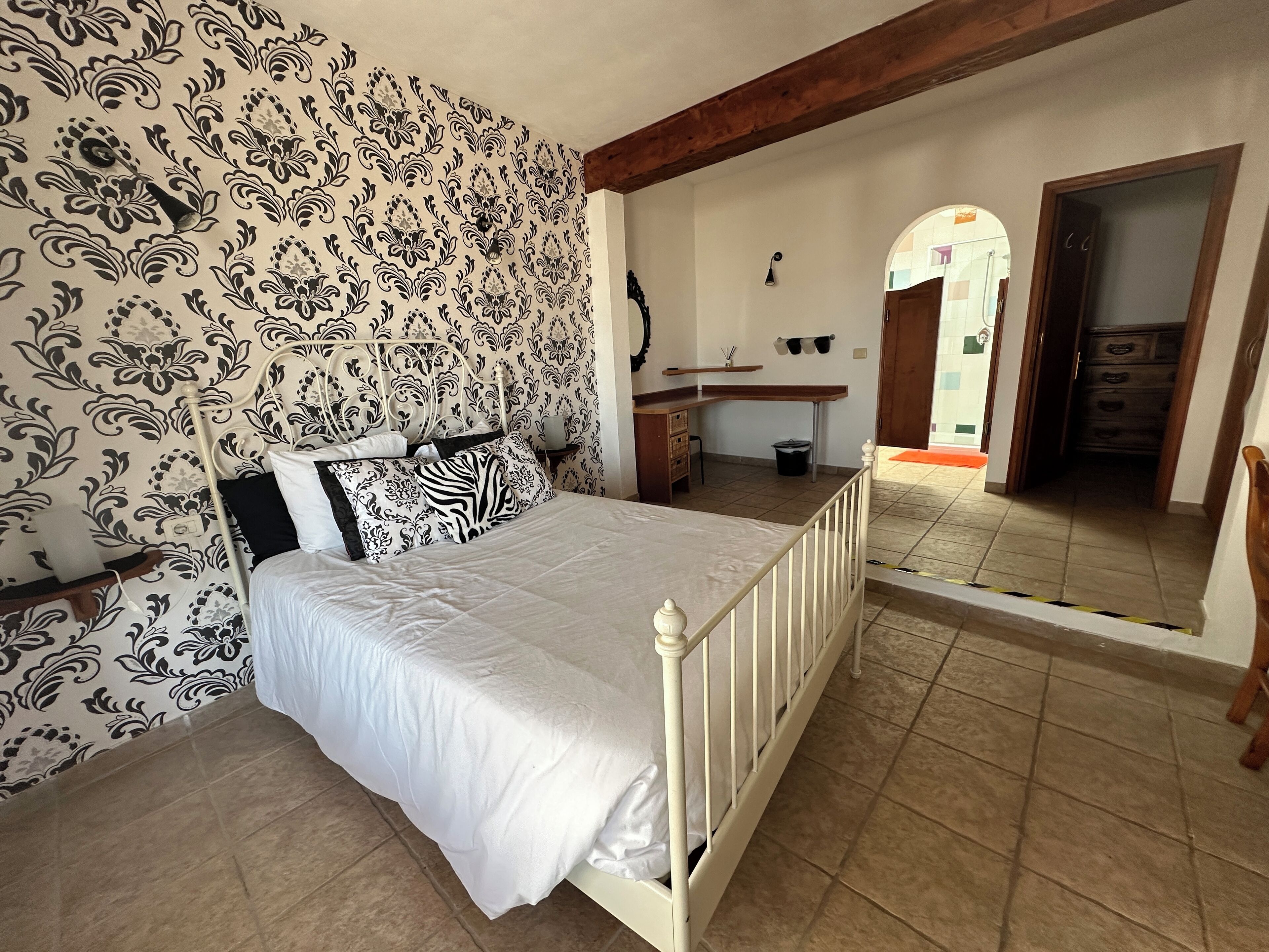 A bedroom with a bed, a desk, and a mirror.