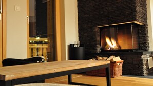 A stone fireplace with a fire, a wooden bench, and a wicker basket.