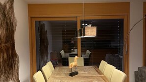 A modern dining area with a wooden table, beige chairs, and a mounted horse sculpture.