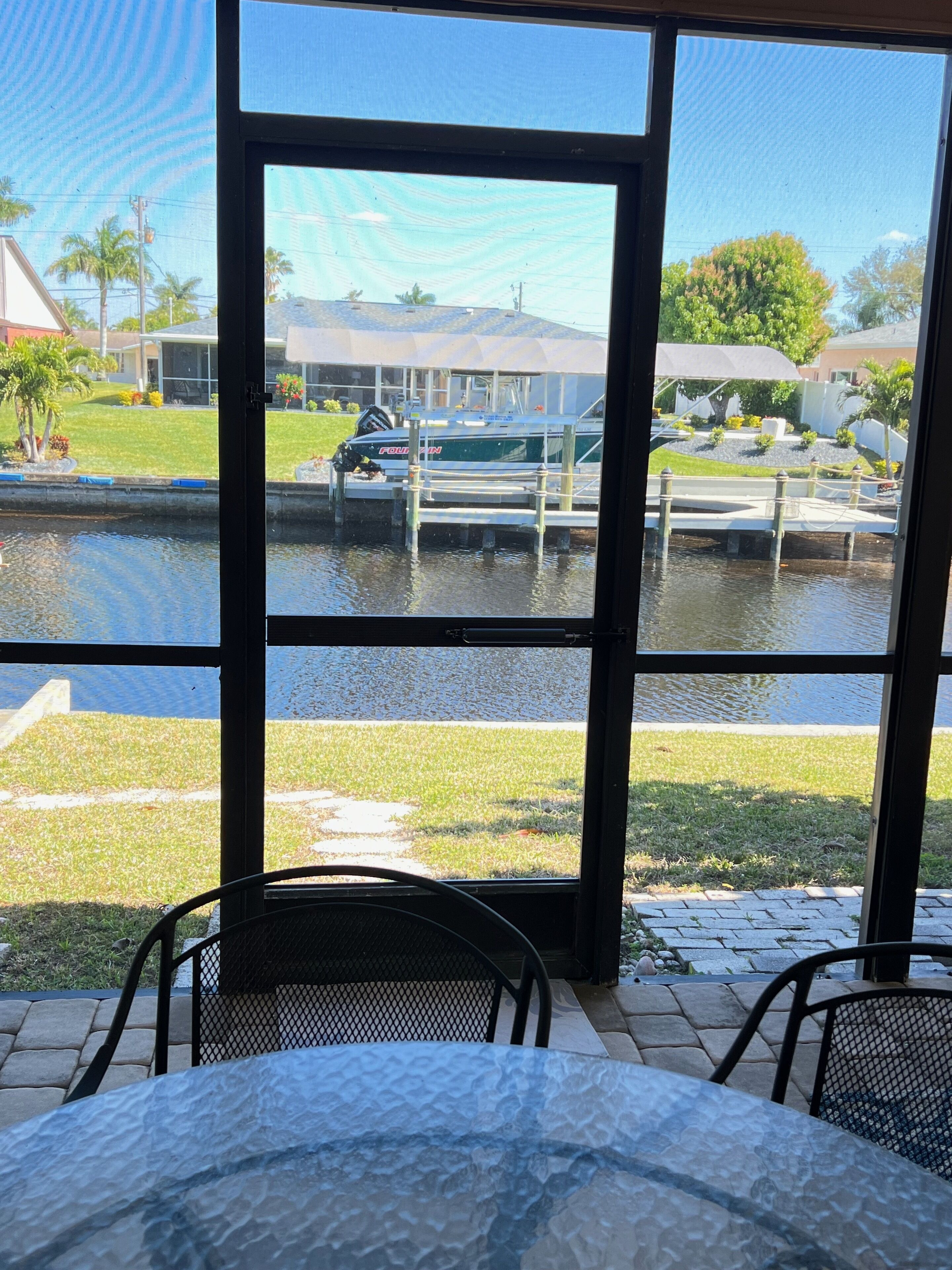 A view from inside a room with a large window overlooking a marina with boats docked.