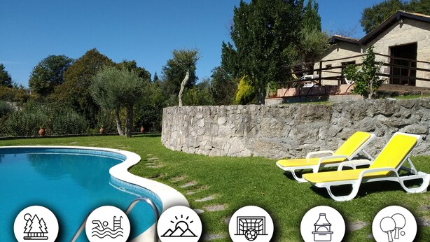 Una piscina con sillones de descanso, un muro de piedra y un edificio con fachada de piedra.