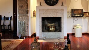 Una sala de estar acogedora con chimenea, pared de piedra y repisa de vidrio con adornos.