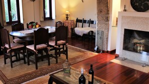 Un comedor con una mesa redonda y sillas, una chimenea y un ventanal con cortinas.