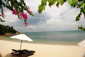 A beach with a white umbrella and two lounge chairs. - four bed room deluxe villa in beach resort idyllic samui (bpphut)