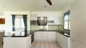 A modern kitchen with white cabinets, a black countertop, and a ceiling fan. - four bed room deluxe villa in beach resort idyllic samui (bpphut)