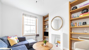 A modern living room with a sofa, a round coffee table, and a bookshelf. - Cool 1 bed in Munster village fulham. (London)