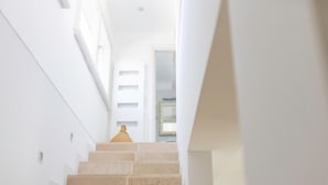 Una escalera con escalones color beige que lleva a un rellano con una pared blanca y una ventana.