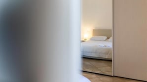 Un dormitorio con una cama, una mesita de noche y una lámpara de pared.