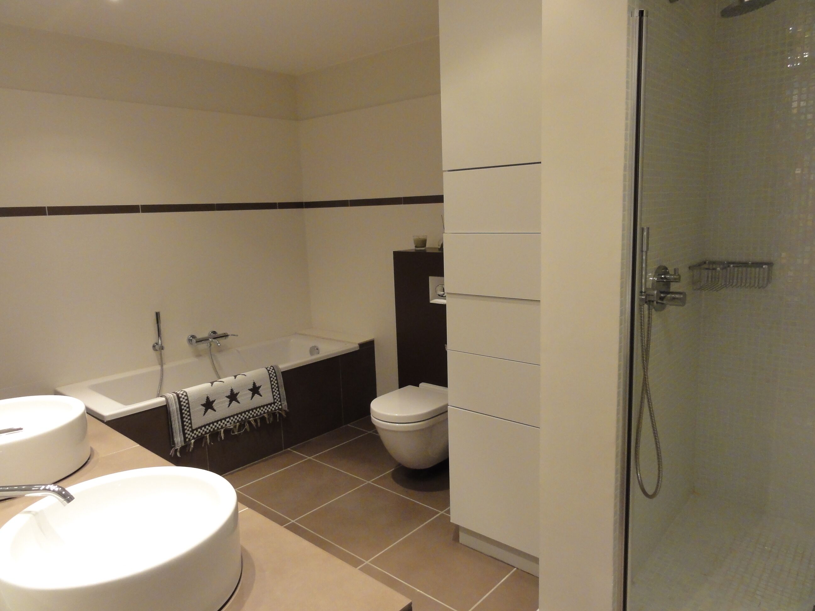 A modern bathroom with a bathtub, toilet, and shower.