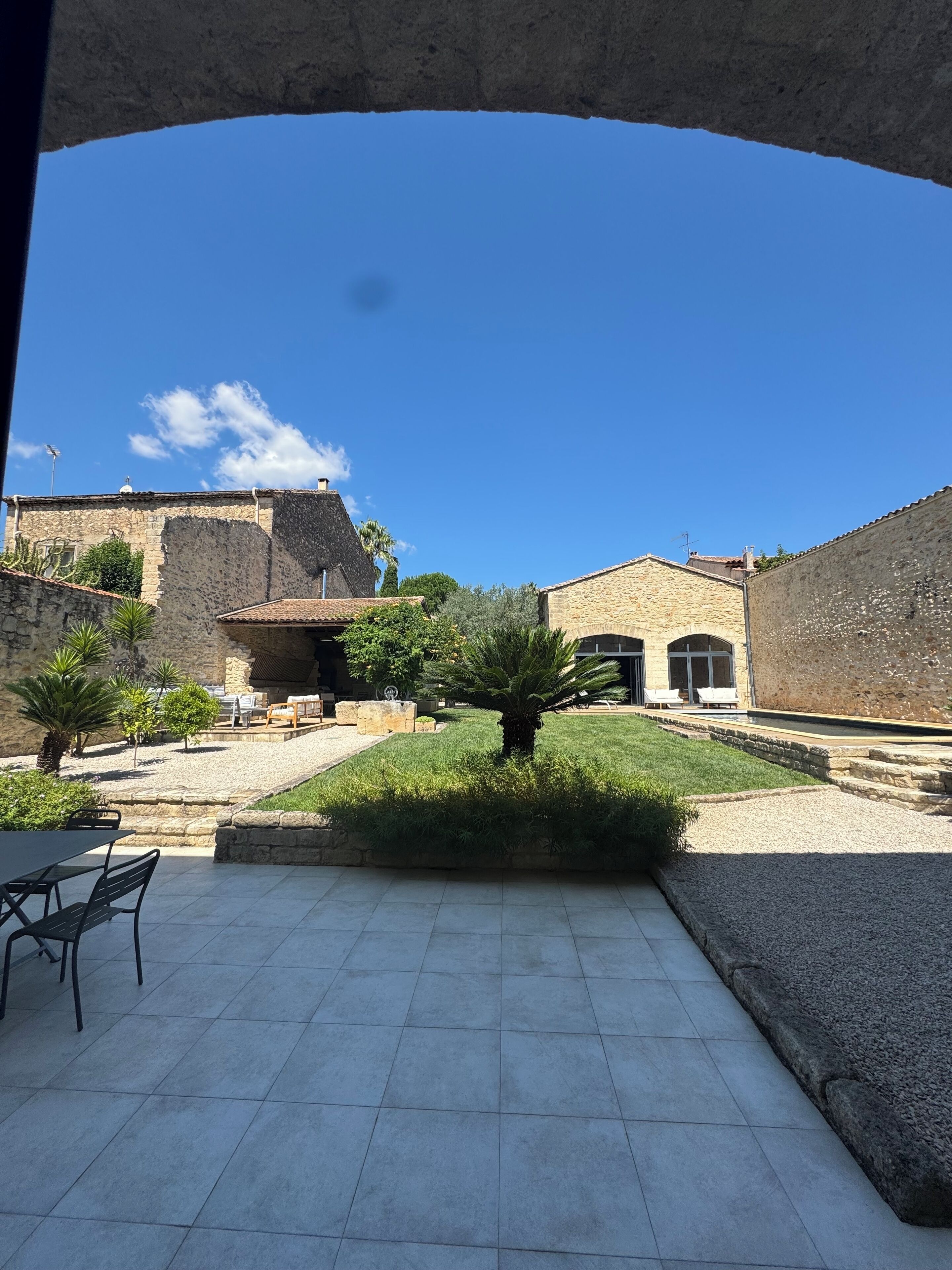 An outdoor courtyard with stone buildings, a palm tree, and a tiled patio area.