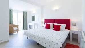 Une chambre d’hôtel avec un lit, un bureau, une chaise et une fenêtre.