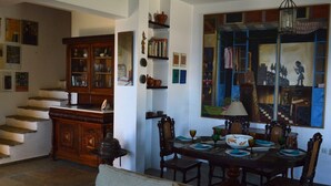 A dining area with a wooden table set for four, surrounded by chairs. A staircase with a wooden railing is visible in the background. - Country villa with amazing view, close to important sites and beaches. (Korinthia)