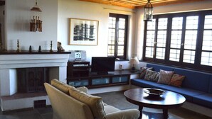 A living room with a fireplace, a sofa, a television, and a large window with multiple panes. - Country villa with amazing view, close to important sites and beaches. (Korinthia)