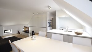 A modern kitchen with white cabinetry, a dining area with a white table and chairs, and a small black vase on the table. - 2 Bedroom apartment near center Ghent (Gent)