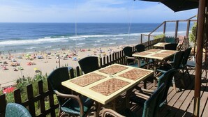 Een terras aan het strand met tafels en stoelen, met uitzicht op de oceaan.