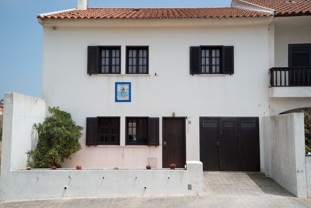 A two-story building with a white facade, black shutters, and a tiled roof.