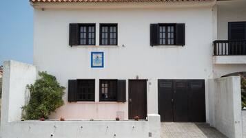 A two-story building with a white facade, black shutters, and a tiled roof.