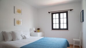Une chambre à coucher avec un lit, une fenêtre, une chaise et une table de chevet.