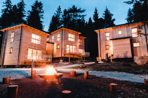 A cabin-style building with multiple levels and large windows, surrounded by trees.