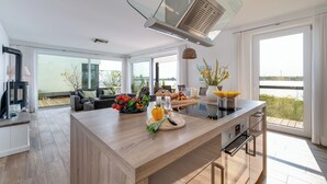 Een moderne keuken met een centraal eiland, grote ramen en uitzicht op de omgeving.