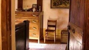 A narrow hallway with a wooden door on the right, a wooden bench on the left, and a small table with a chair in the center. - Typical home country quaint with antique furniture (cineto romano)