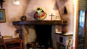 A cozy room with a fireplace, a wooden table, and a chair. - Typical home country quaint with antique furniture (cineto romano)