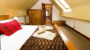 A bedroom with a bed, a wooden wardrobe, a nightstand, a radiator, and a skylight. - Granary at Oaks Barn Farm, Kadai fire bowl & optional hot tub, country location (Alcester)