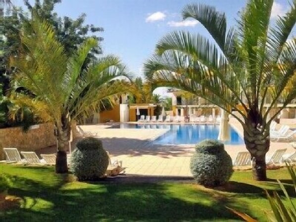 A swimming pool surrounded by palm trees and lounge chairs. - RESORT VACATION WITH POOLS, SEA VIEW, TERRACE, WIFI AND AIR CONDITIONING (tavira)