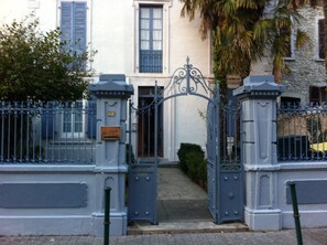 A gated entrance with a wrought iron gate, a stone wall, and a small gatehouse. - Beautiful T3 "design", 4 *, quiet in the garden, town center -2 bedrooms, 2/5 people (Lourdes)