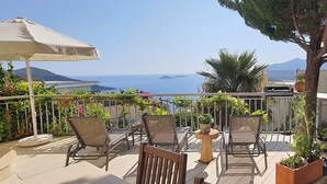 Una terrazza con posti a sedere all'aperto, un tavolo e una pianta in vaso.